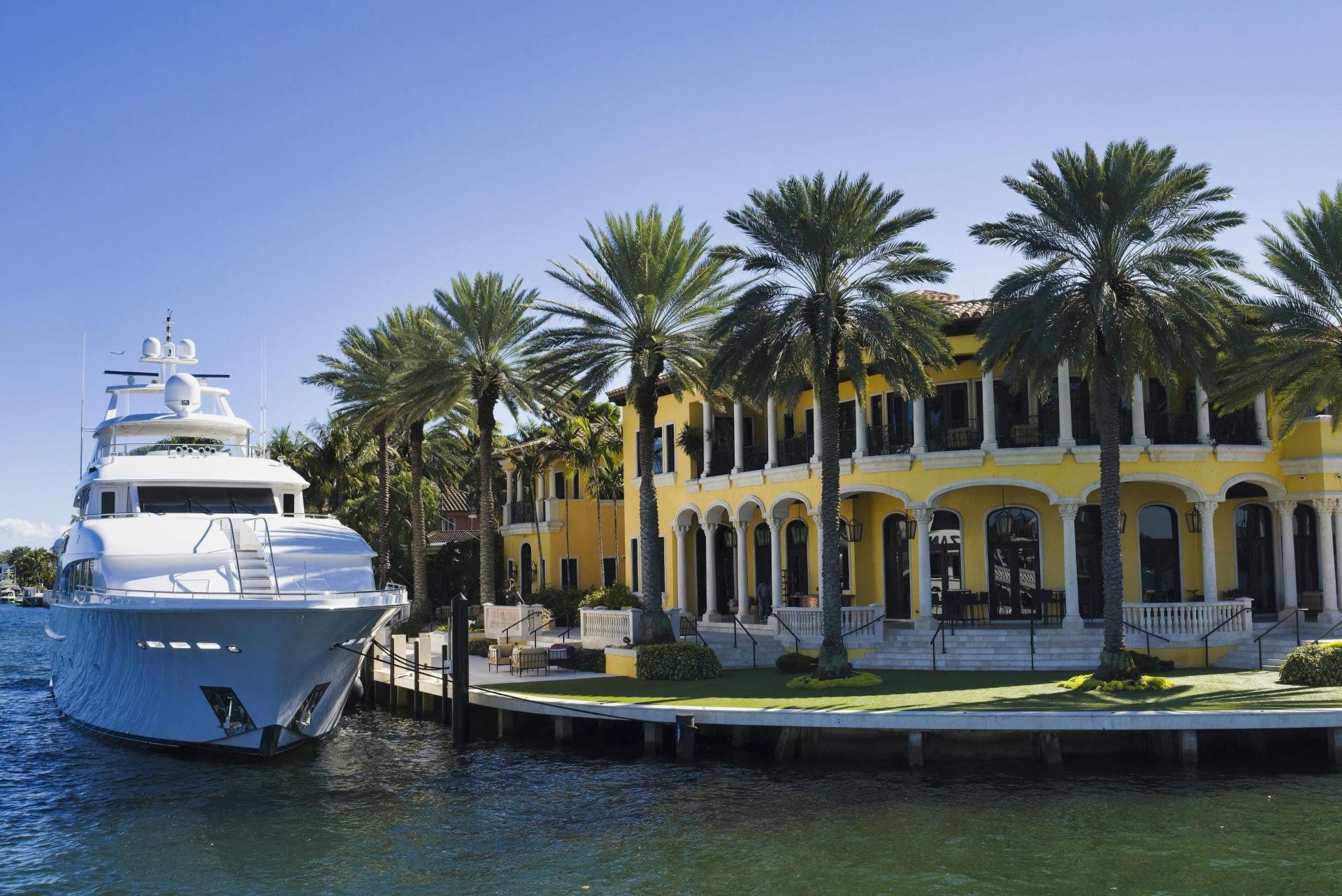A stunning view of a luxury yacht docked beside a grand mansion in Fort Lauderdale, Florida.