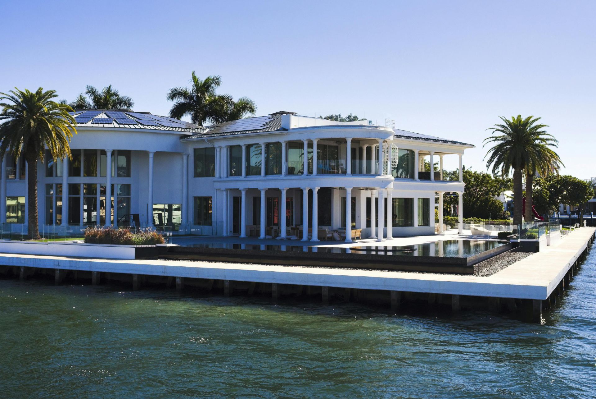 Stunning modern mansion with palm trees by Florida waterfront, perfect for luxury living.