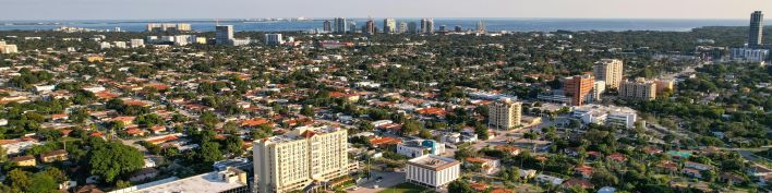 Aerial daytime view of Miami, Florida capturing city skyline and distant ocean.